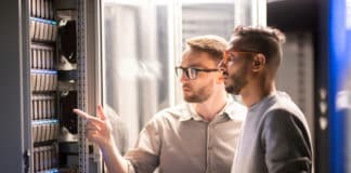 A pair of IT pros review a server in a data center.