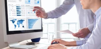 Employees work on data analytics on a computer in an office.
