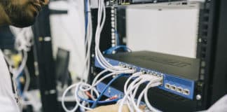 An employees connects a cable to a networking switch.
