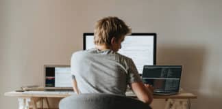 A software engineer works on application containers with a computer at their workstation.