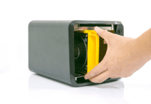 Man holding a storage drive inside a black NAS device.