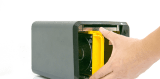 Man holding a storage drive inside a black NAS device.