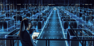 Female IT specialist using tablet computer overlooking a data center.