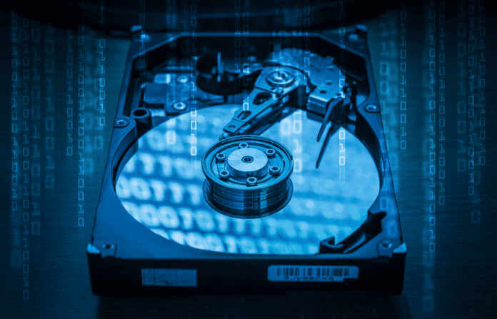 Abstract image of inside of hard disk drive and binary code hologram on top.